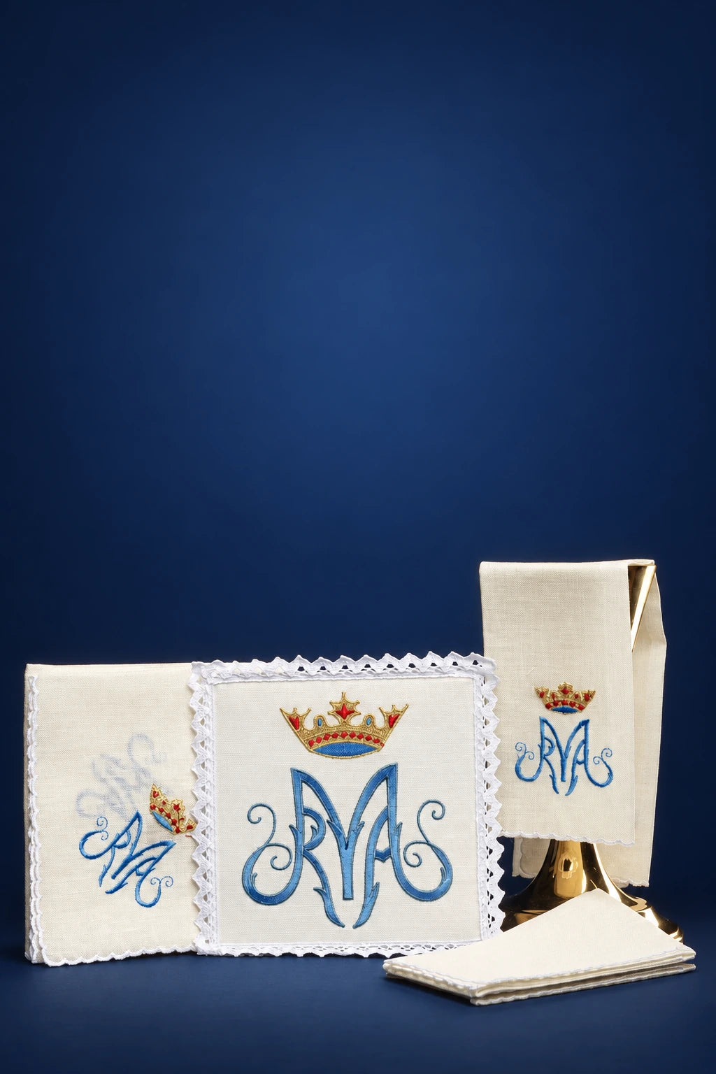 Altar linen set with Marian monogram and crown embroidery, shown folded with scalloped lace trim