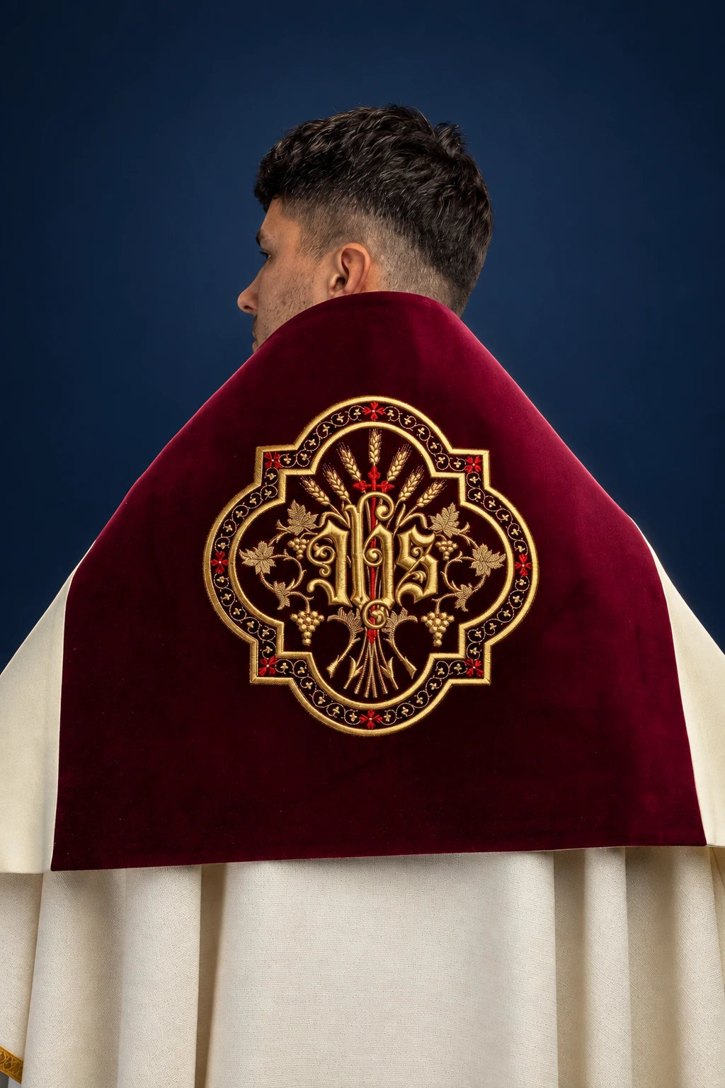 Back view of a burgundy velvet humeral veil with embroidered IHS motif and gold trim