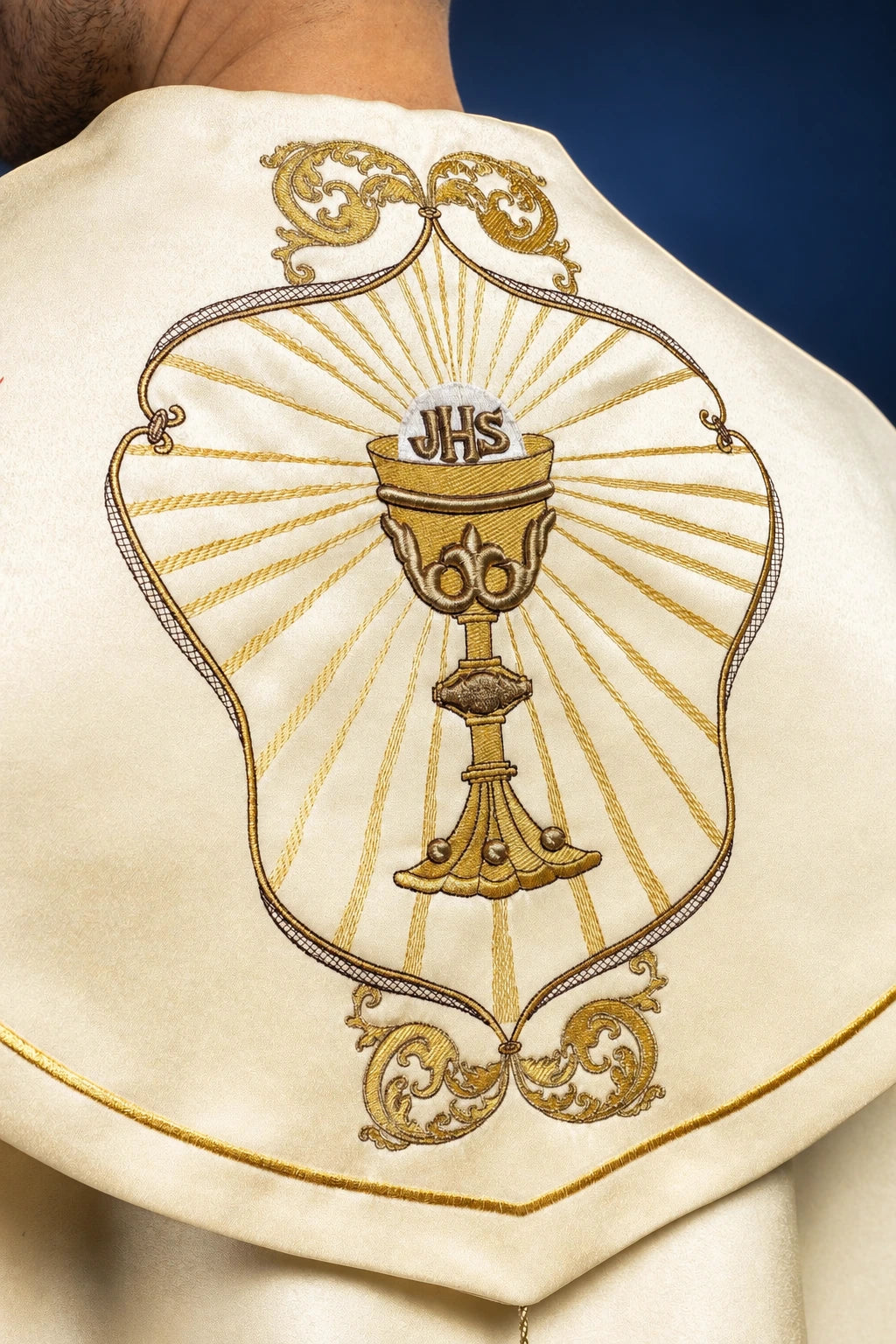 Back view close-up of the ecru cope hood with a chalice, IHS, and radiating gold embroidery
