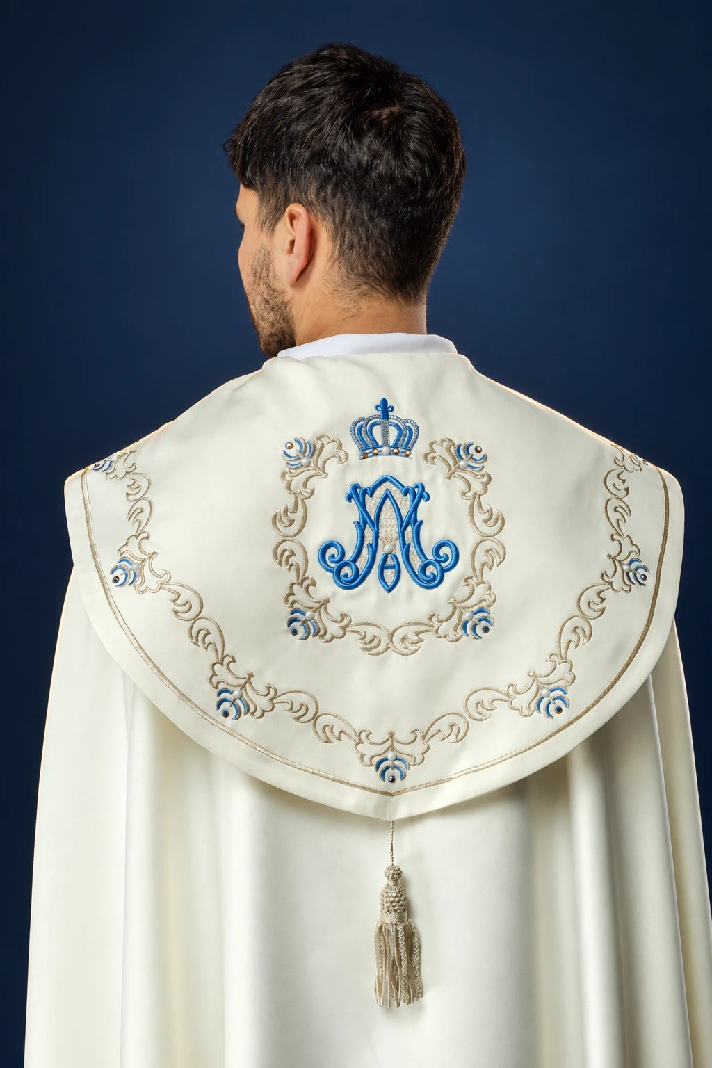 Back view of a cream cope with embroidered Marian monogram and crown on the cape collar, trimmed with tassel