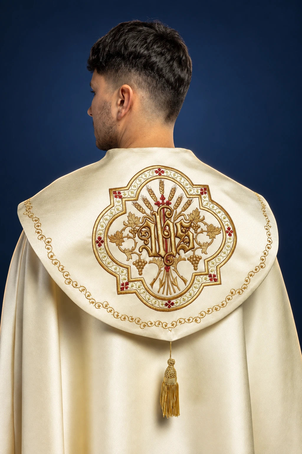 Back view of an ecru satin cope with raised gold IHS embroidery and tassel on the hood