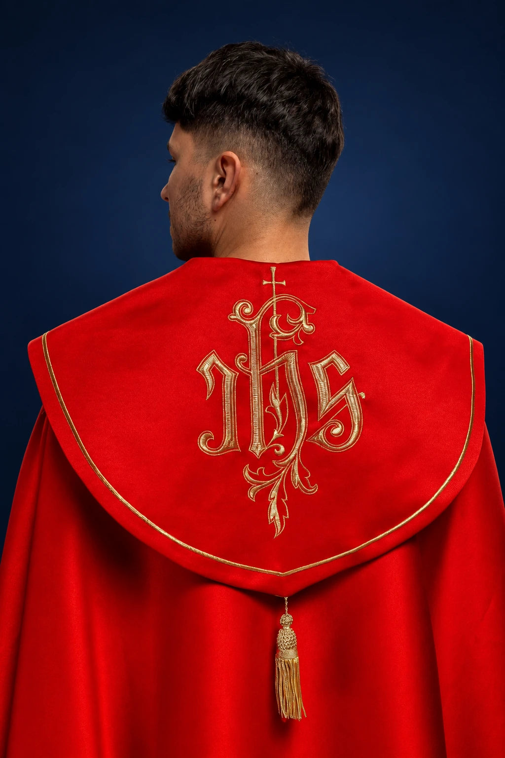 Back view of red cope with gold trim and embroidered IHS monogram on the hood