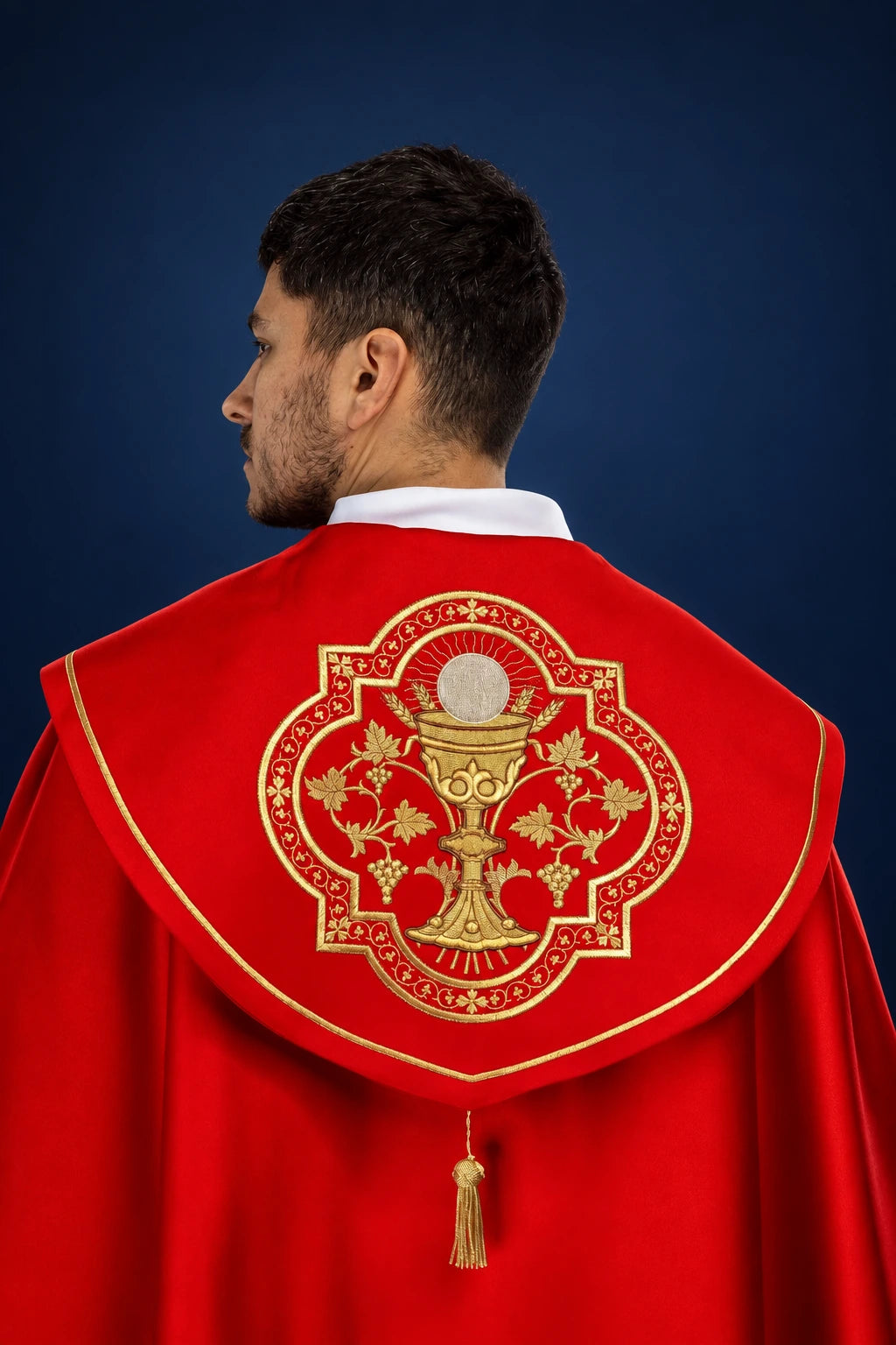 Back view of red liturgical cope with gold embroidered chalice medallion and tassel