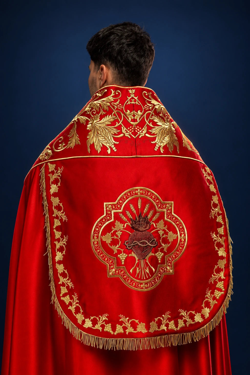Back view of red satin Roman cope with gold embroidery and Sacred Heart medallion on the hood and back panel