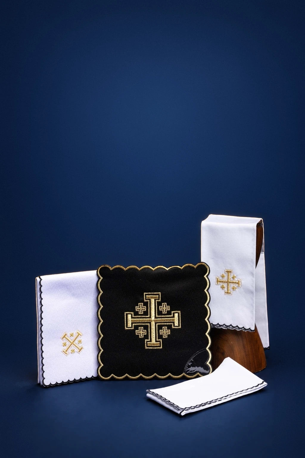 Black altar linen set with gold Jerusalem cross embroidery, shown folded with scalloped edging