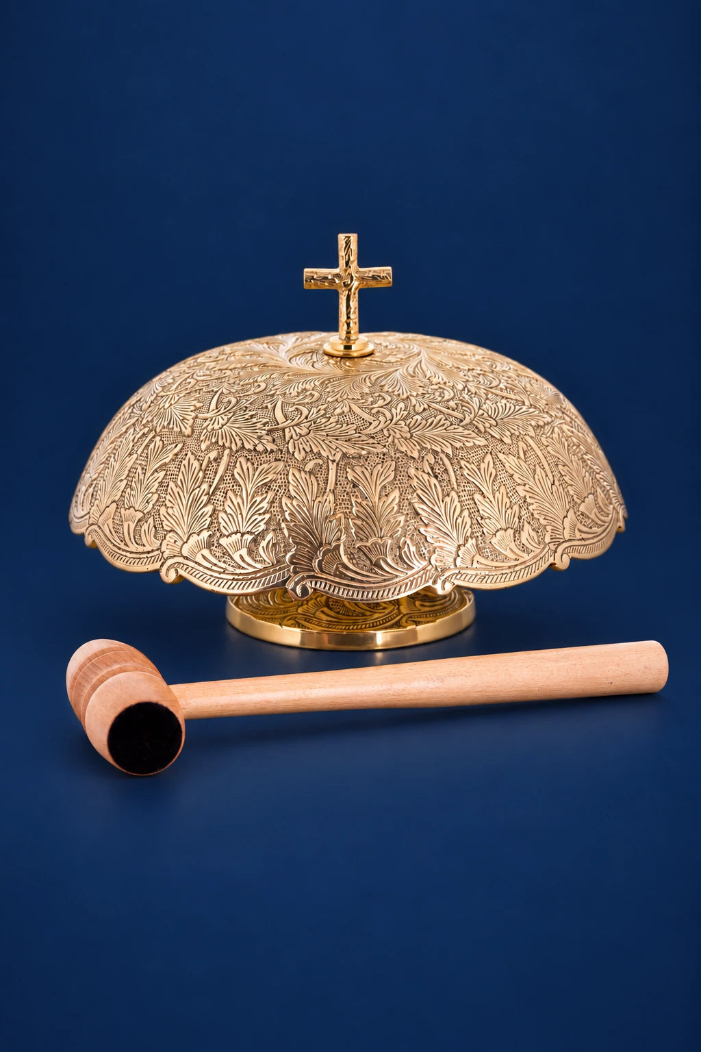 Brass altar bells with engraved dome top, cross finial, and wooden mallet shown front view