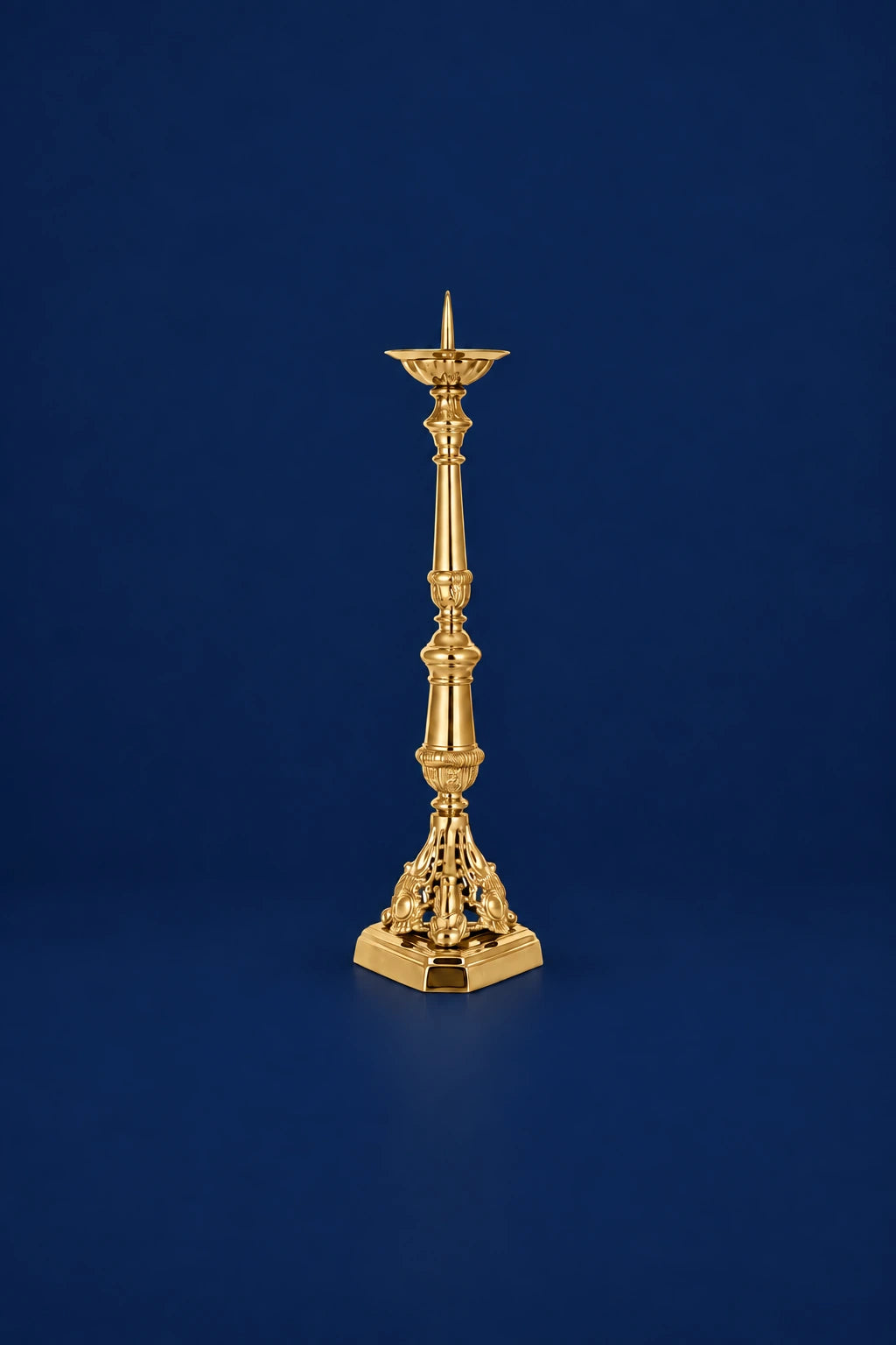 Brass candlestick with gold finish, full view, ornate pierced base and tall taper holder.