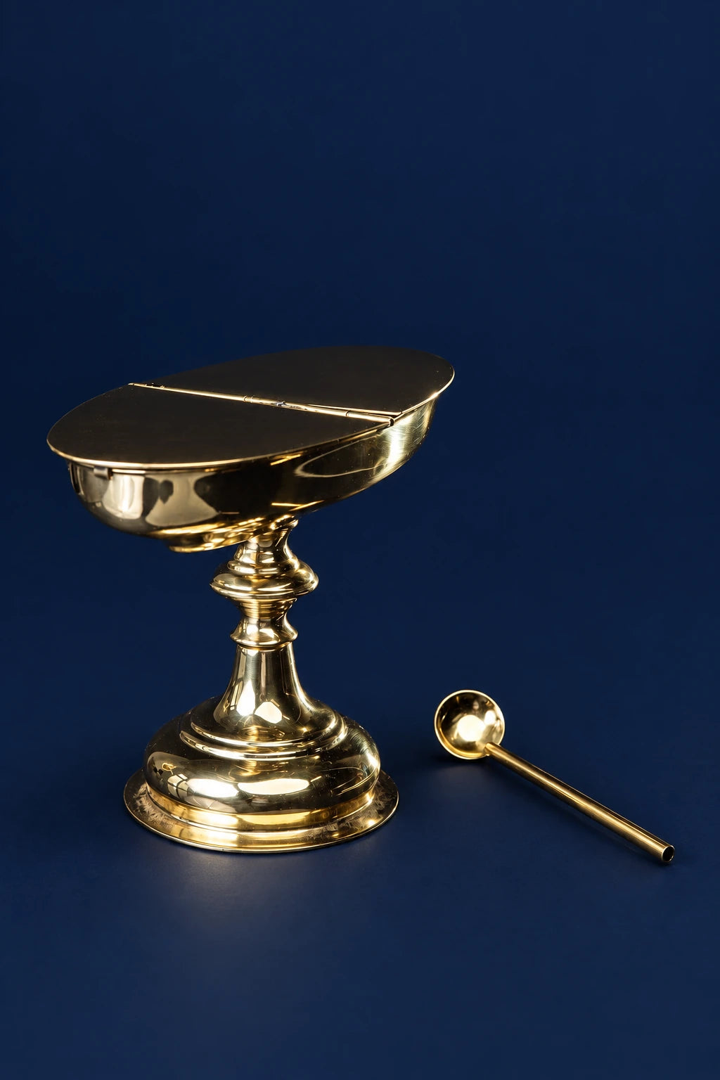 Brass incense boat with spoon, shown in three-quarter view with hinged lid and pedestal base