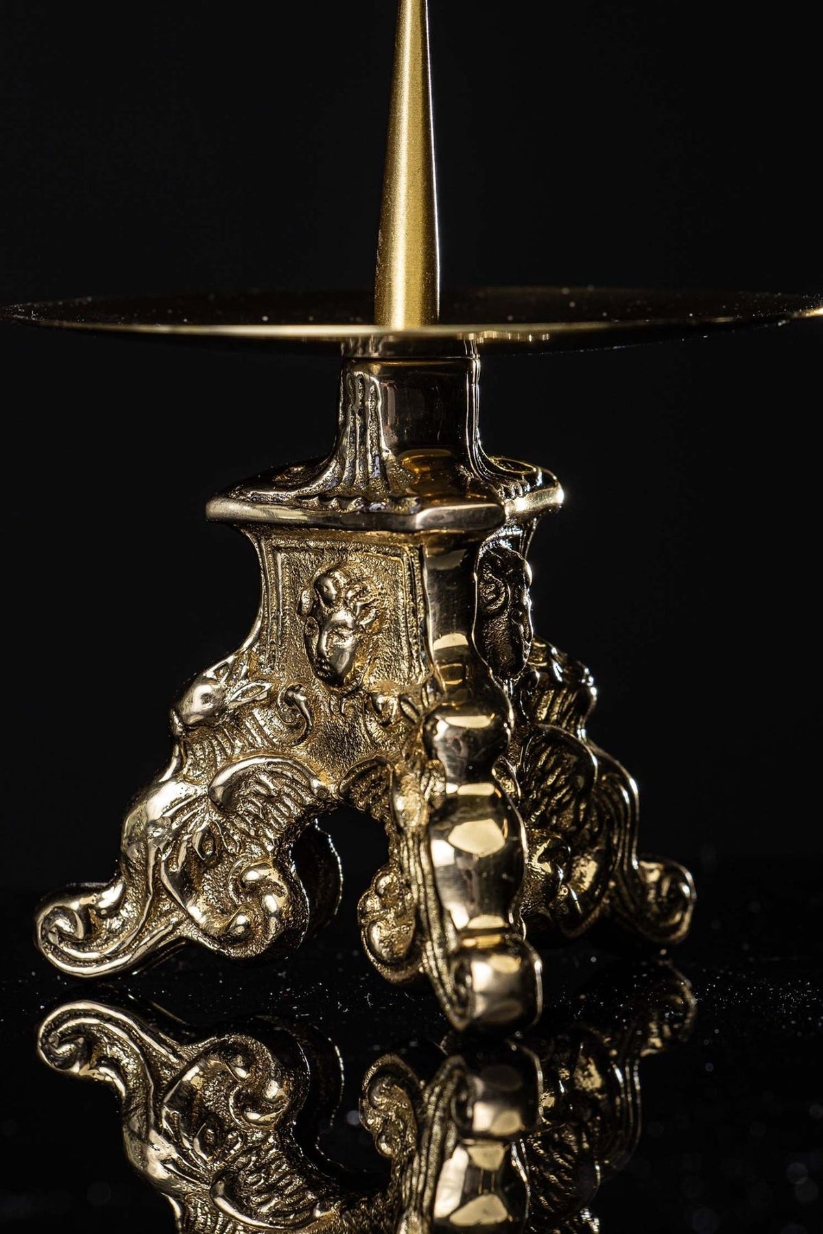 Brass candlestick close-up showing angel relief and ornate scrollwork