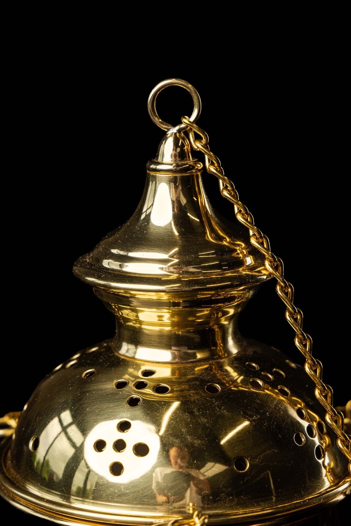 Gold church thurible lid close-up with hanging ring and chain
