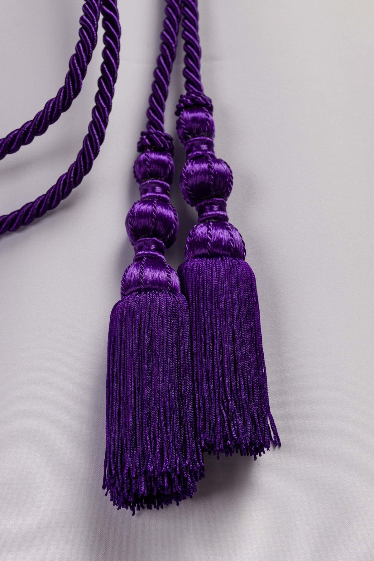 Purple cincture close-up showing two matching braided tassels