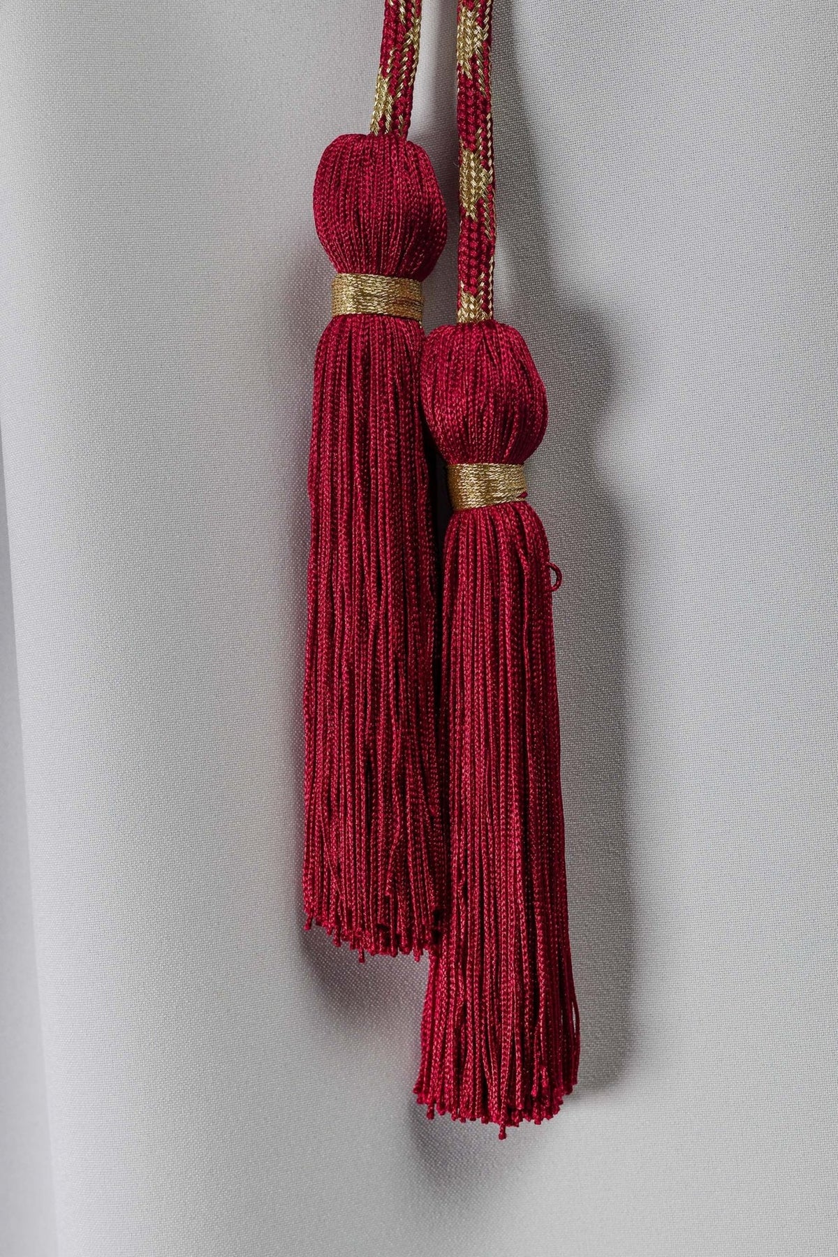 Red and gold cincture close-up showing two red tassels with gold bands
