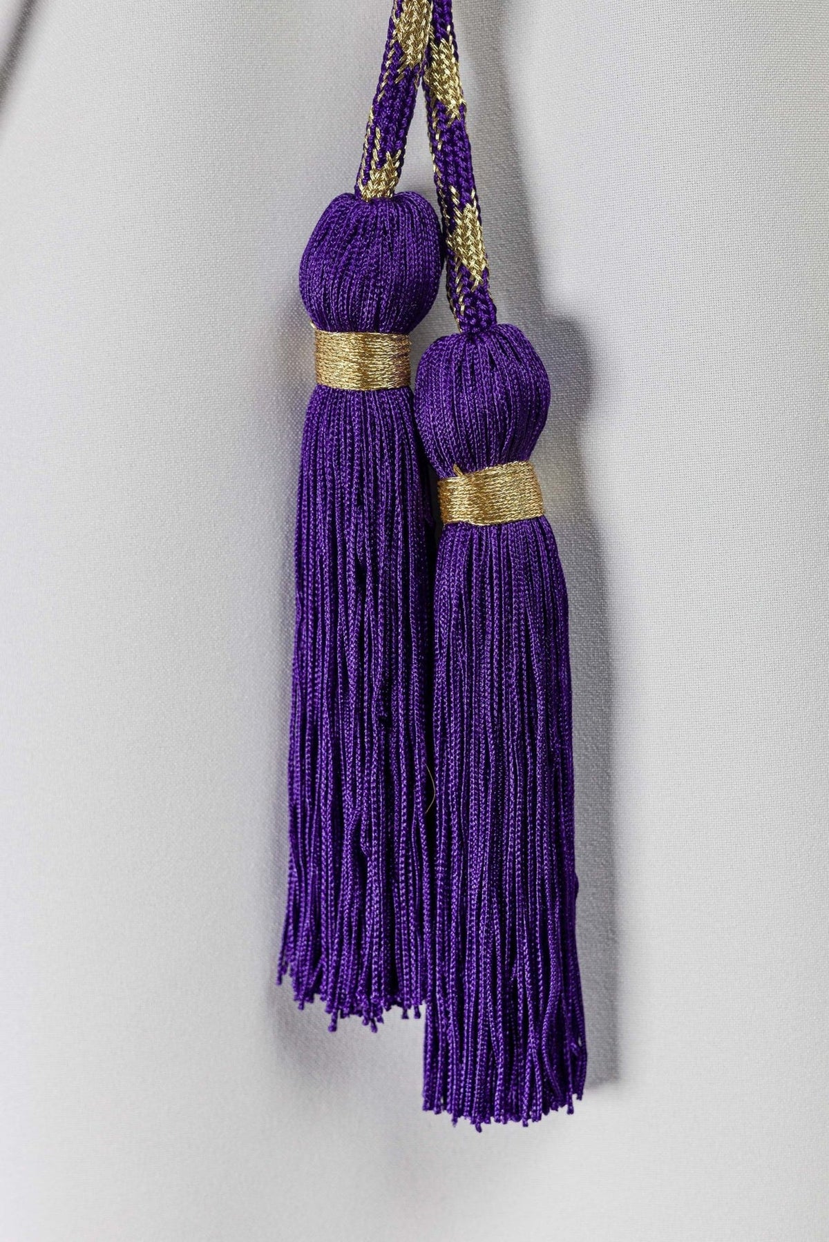 Purple and gold cincture close-up of two purple tassels with gold bands