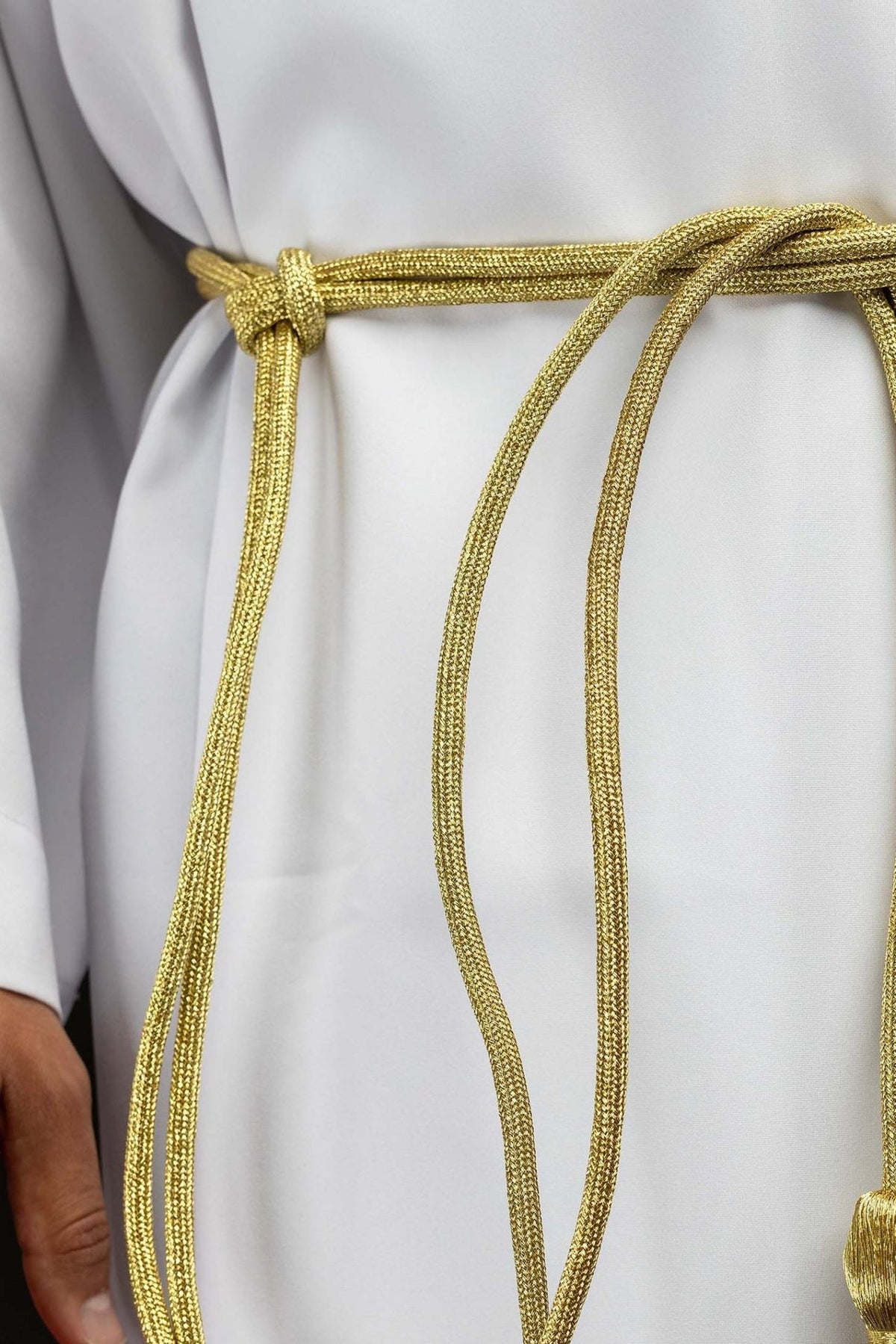 Gold cincture close-up showing the braided cord and tied waist knot