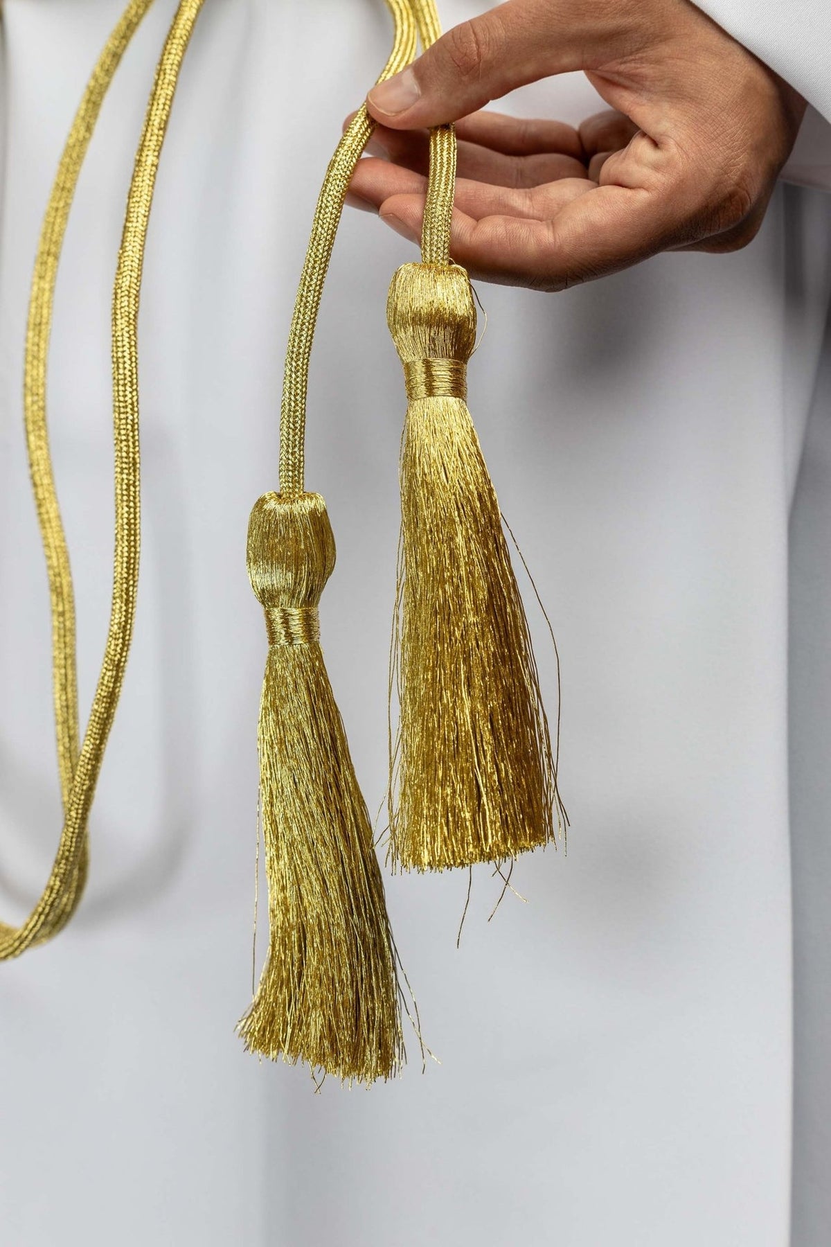 Gold cincture close-up showing two long fringed tassels