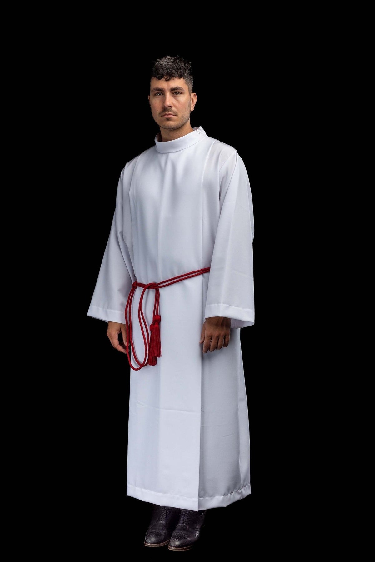 Red liturgical cincture worn with an alb, showing the waist cord and hanging tassels