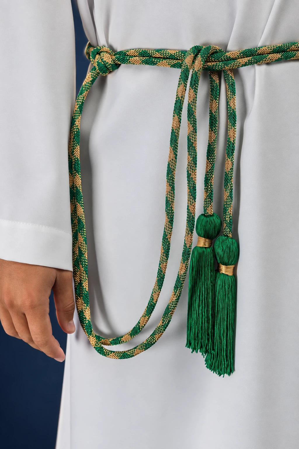 Close-up of a green and gold braided cincture with knotted tassels at the waist of a white alb