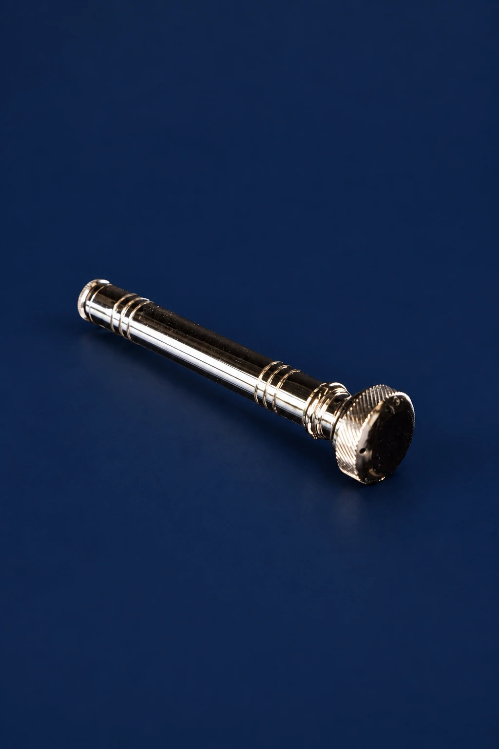 Close-up of a metal aspergillum with a long cylindrical handle and textured rounded sprinkler head