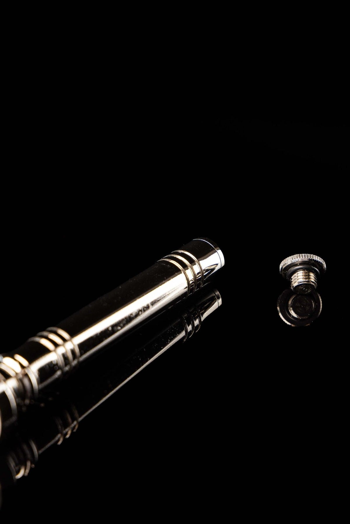 Metal aspergillum close-up of polished handle, decorative rings and separate threaded cap