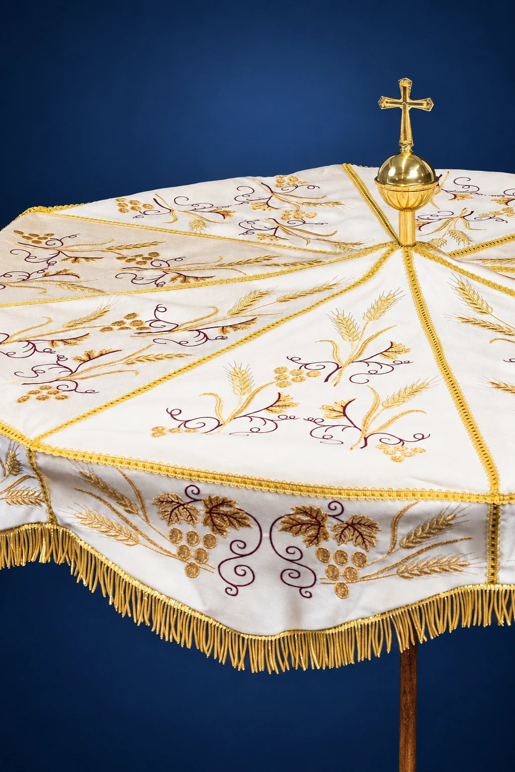 Ecru processional umbrella, close-up of the top panel with gold embroidered wheat and vines and a gold cross finial