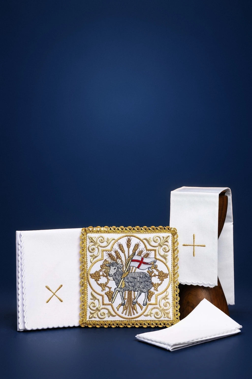Embroidered altar linen set with Agnus Dei motif, shown folded with cross embroidery and chalice cover