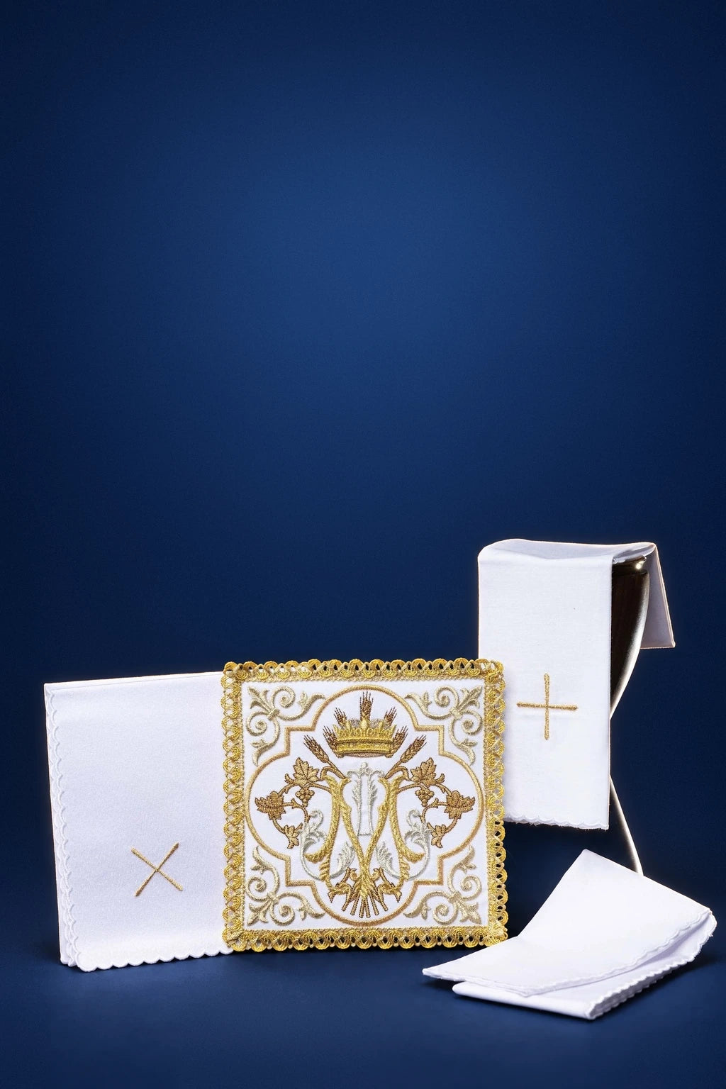 Embroidered altar linen set with gold Marian emblem, folded corporal, purificator, pall, and lavabo towel