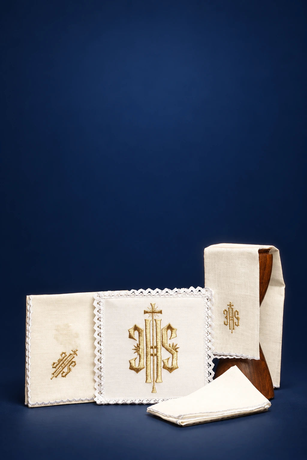 Embroidered altar linen set with IHS monogram, featuring a folded corporal, purificator, and pall with scalloped trim