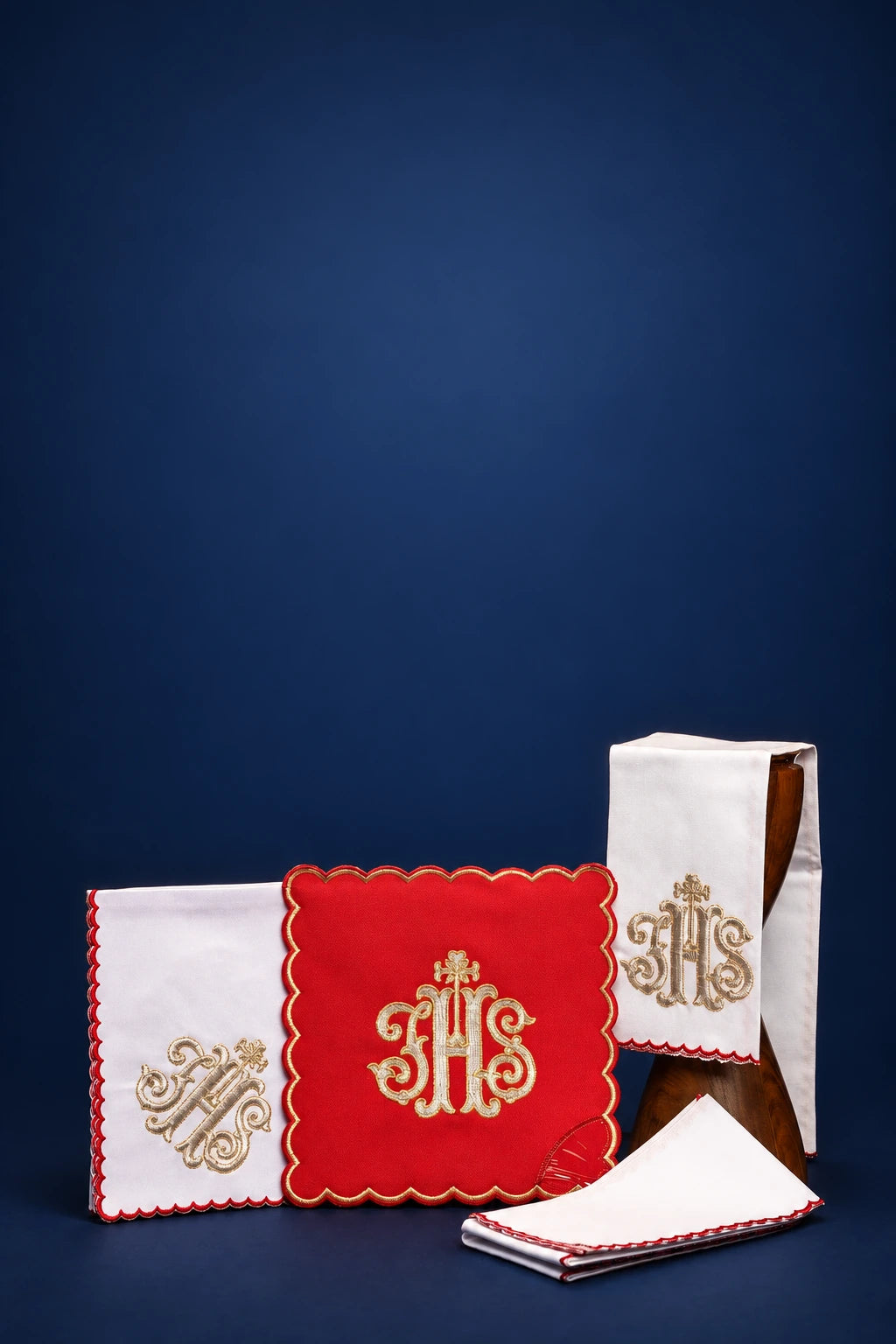 Embroidered red altar linen set with IHS monogram and scalloped trim, shown folded and displayed together