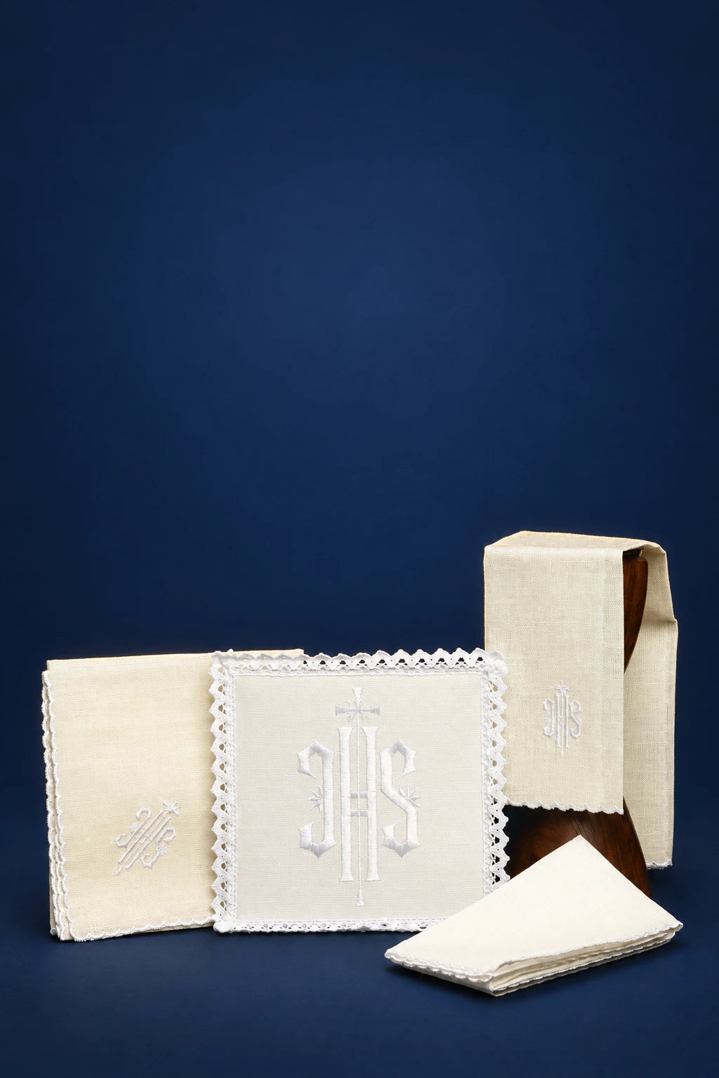 Embroidered white altar linen set with IHS monogram, shown folded and stacked