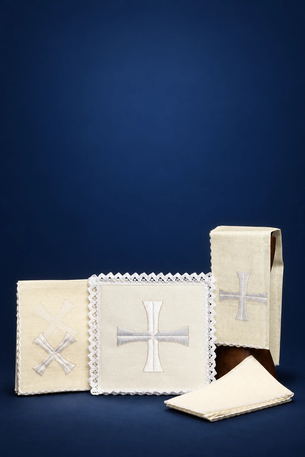 Four altar linens with cross embroidery, including one scalloped cloth and a folded corporal set
