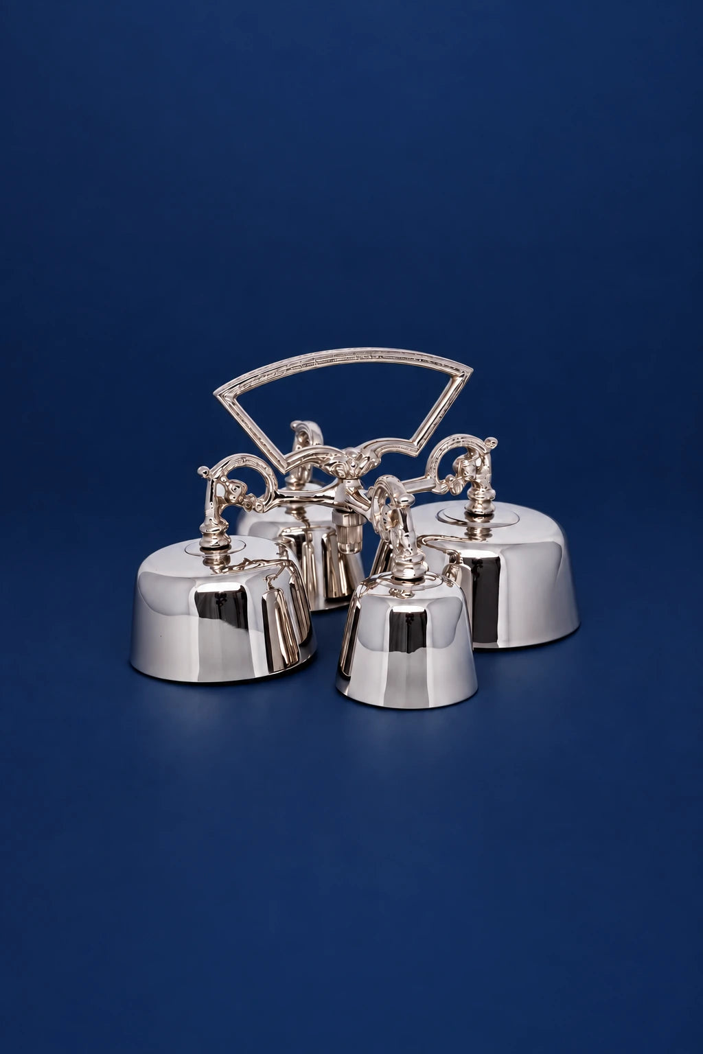Four nickel-plated brass sanctus bells, front view, with arched handle and polished finish