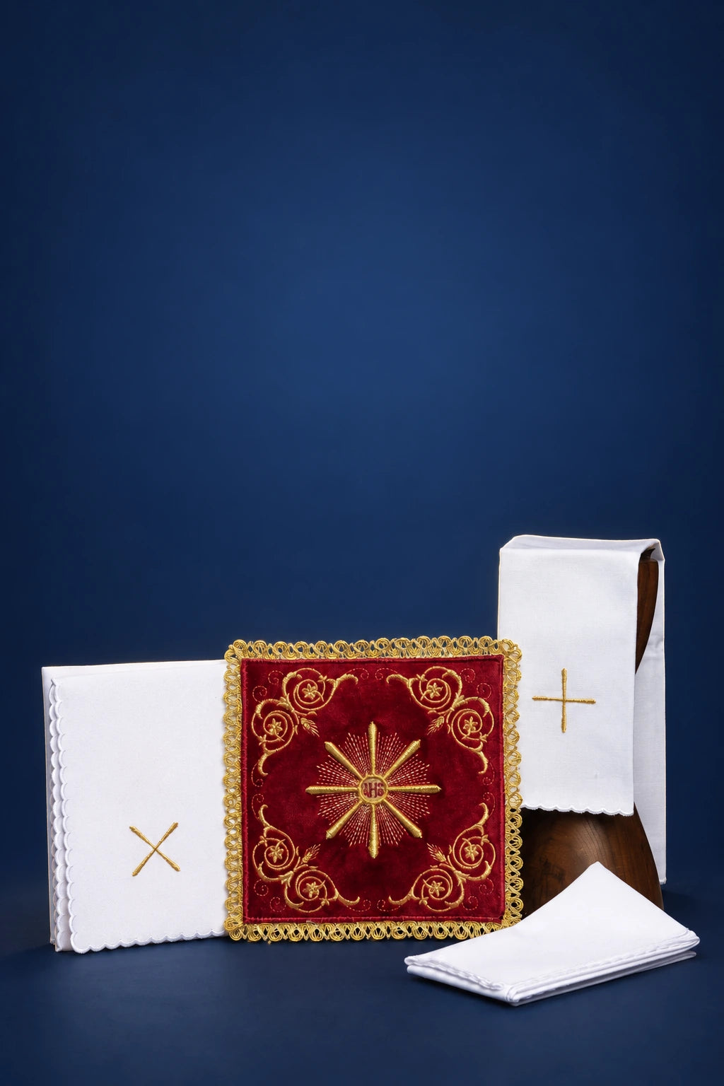 Front view of altar linen set with embroidered red velvet chalice pall, folded corporal, purificator, and pall veil with