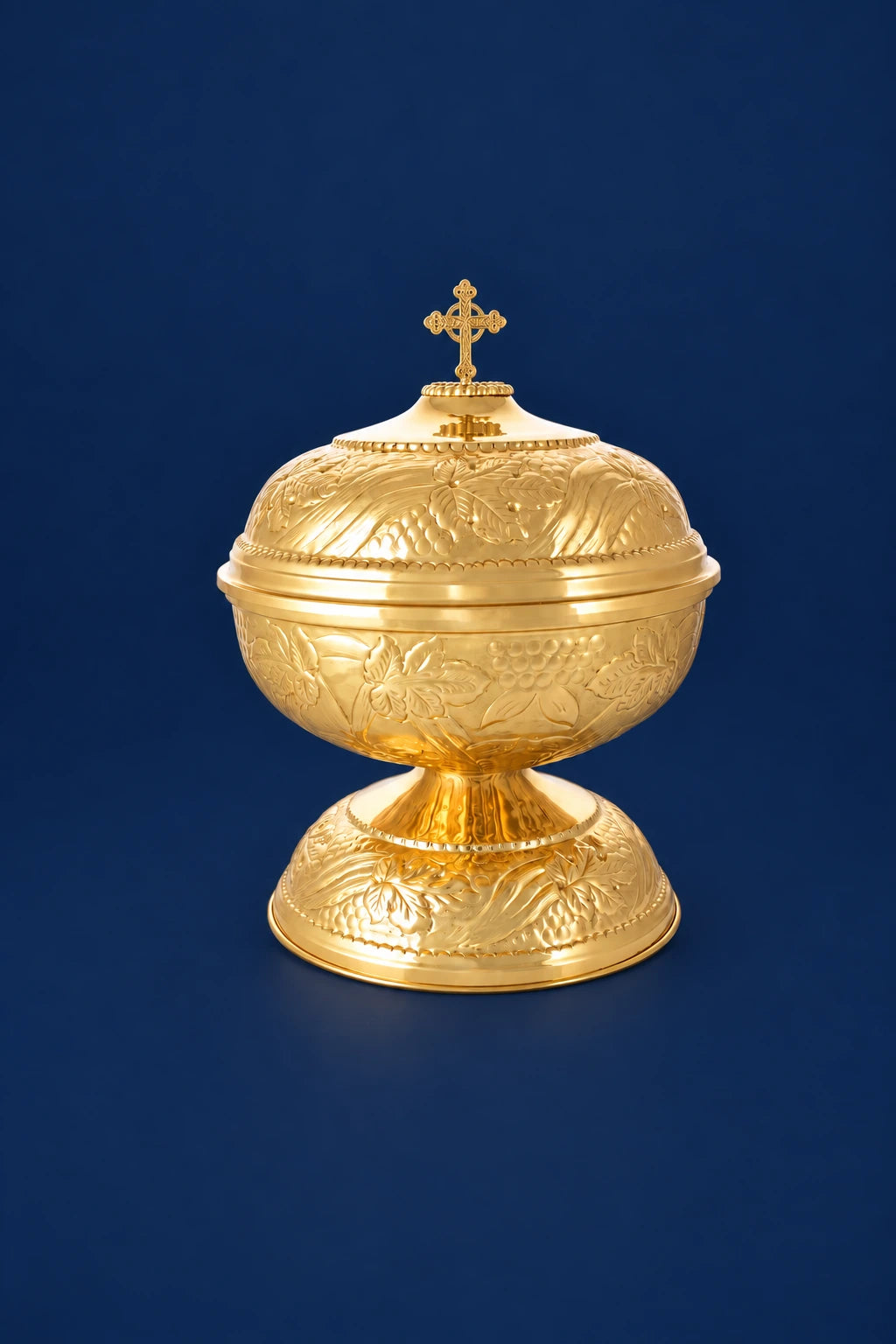 Front view of a brass baptismal font with vine motifs and a cross finial on top