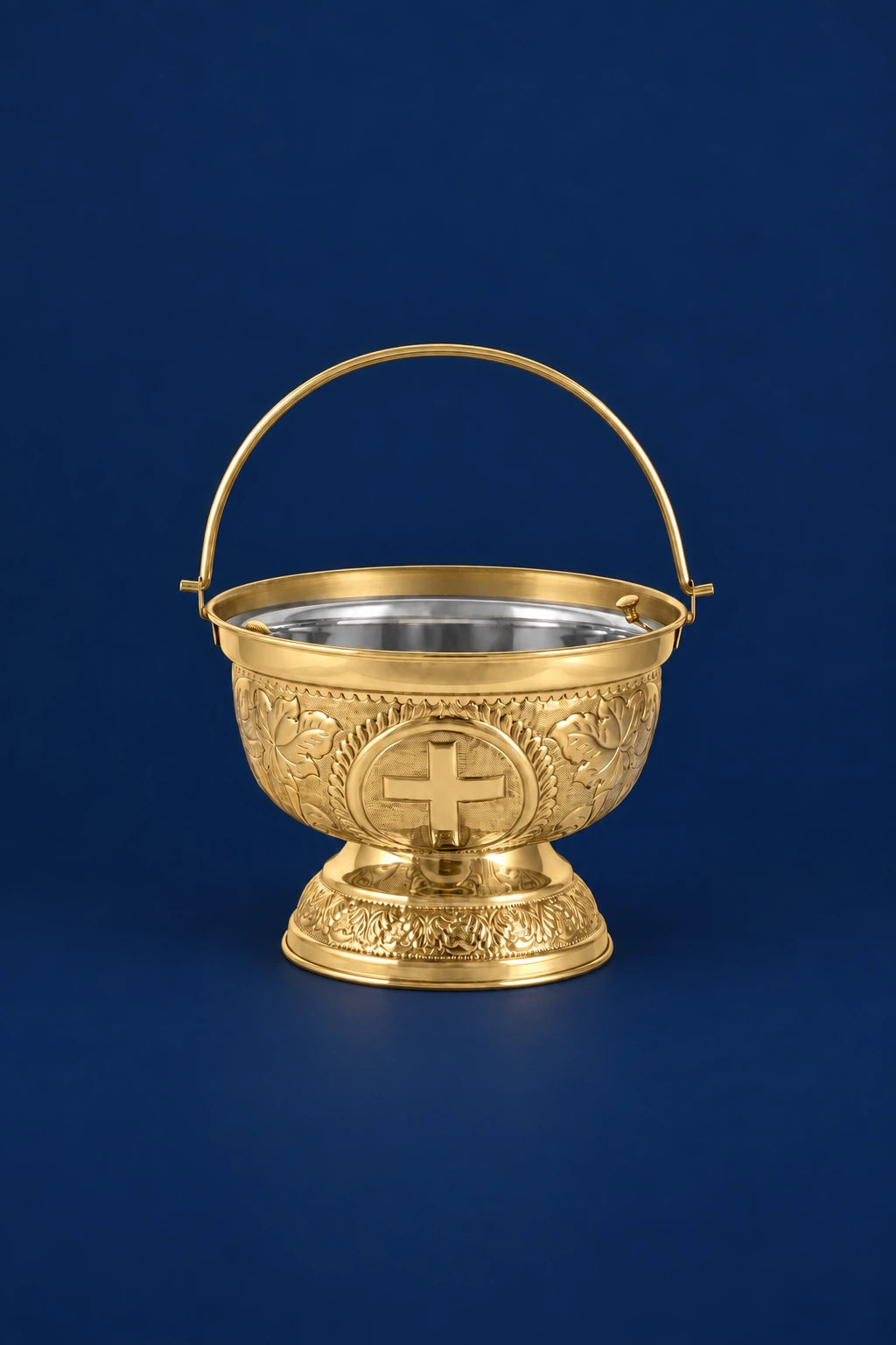 Front view of a brass holy water bucket with handle, cross medallion, and ornate floral engraving