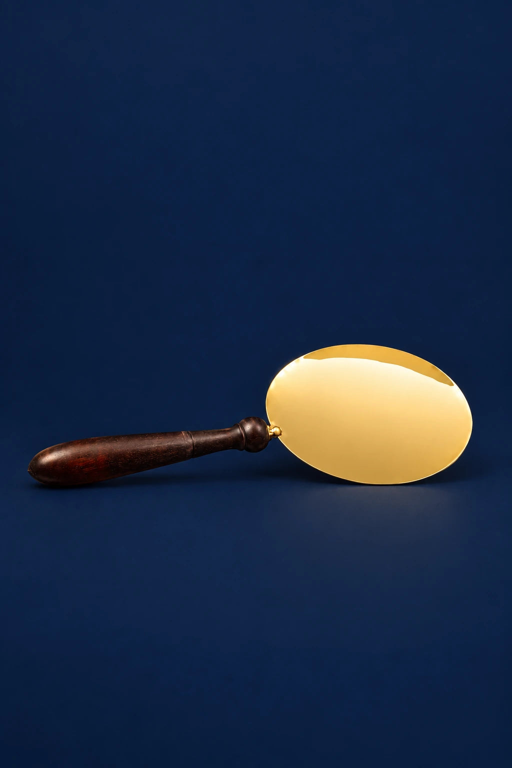 Front view of a communion paten with wooden handle and oval gold plate