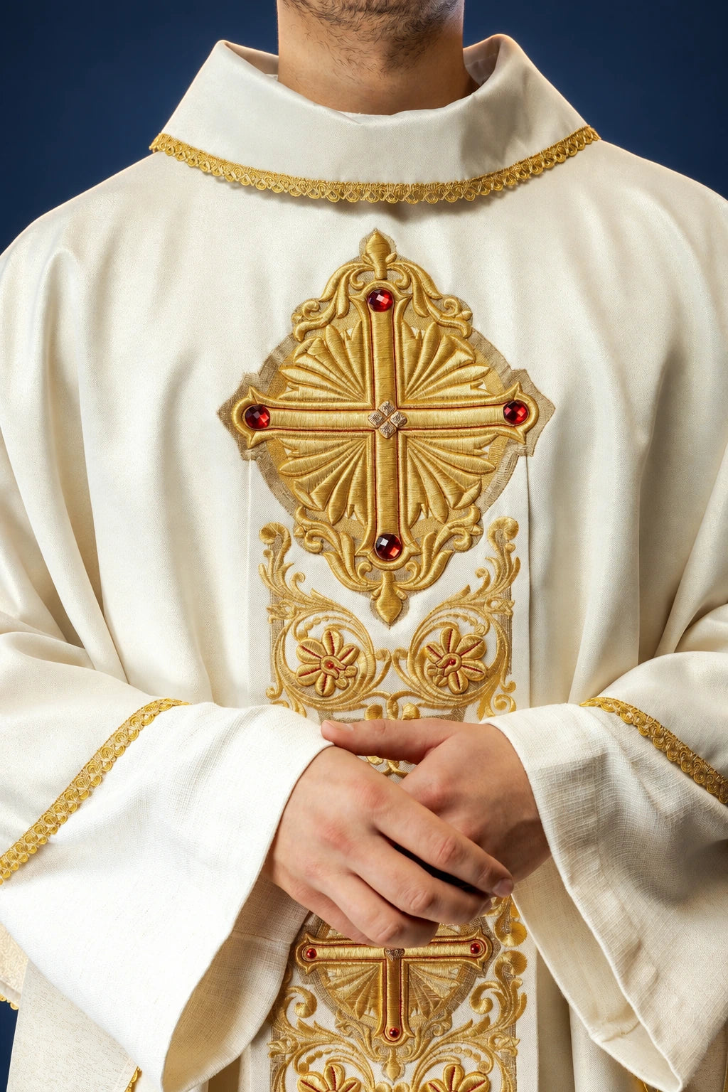 Front view of a cream chasuble with gold embroidery, large cross motif, and red stones