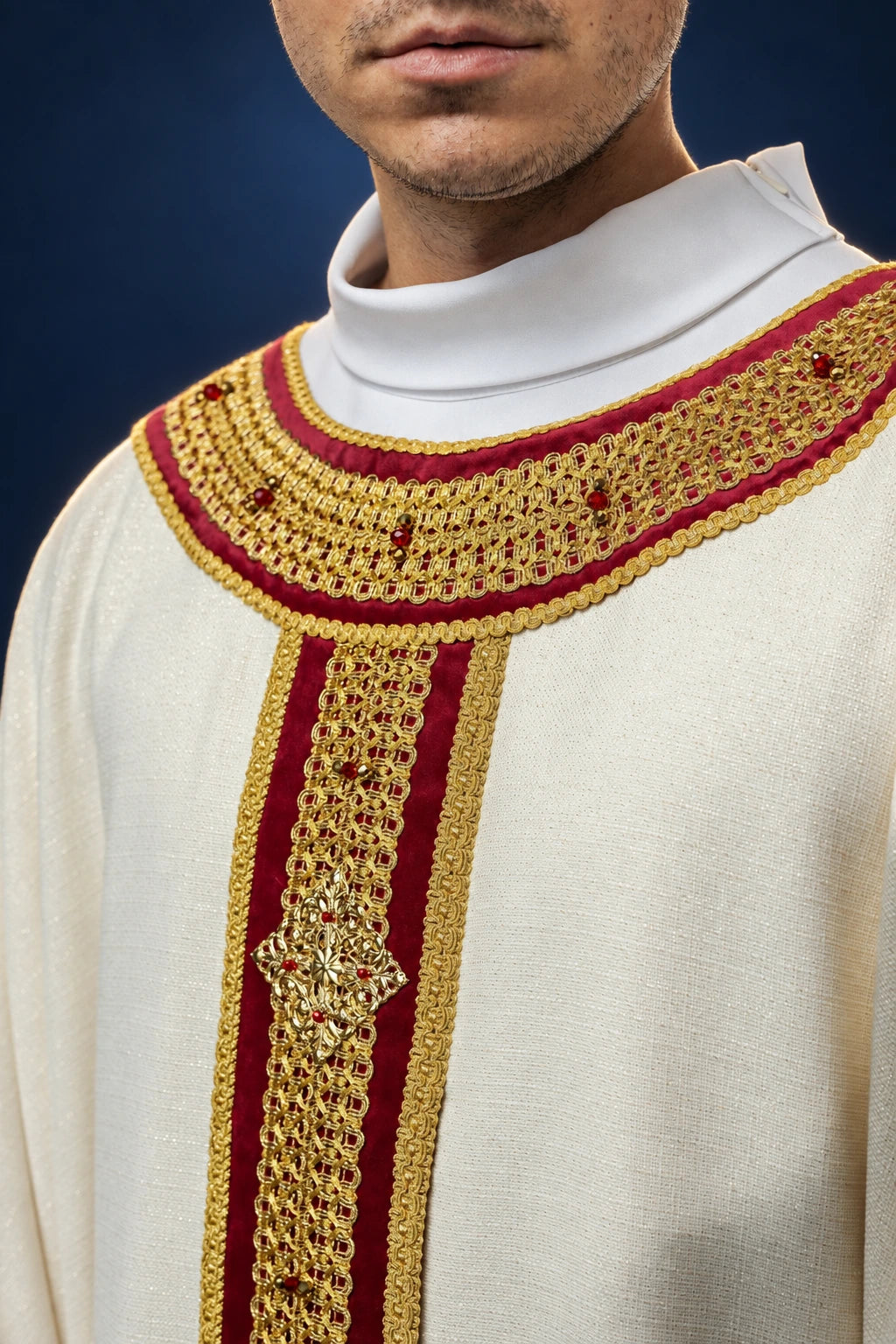 Front view of a cream chasuble with red-and-gold beaded or stone trim and central vertical ornamentation.