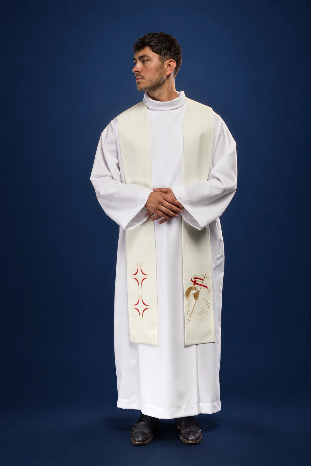Front view of a cream priest stole worn over a white alb, with red star motifs and a lamb panel