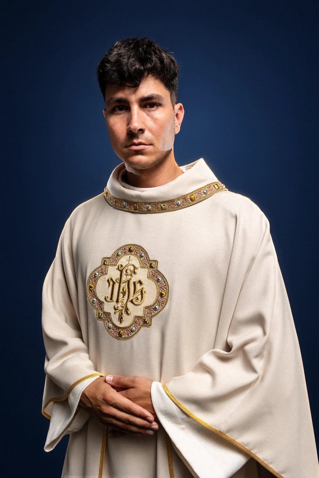 Front view of an ecru Catholic chasuble with IHS embroidery and gold trim on the neckline and sleeves