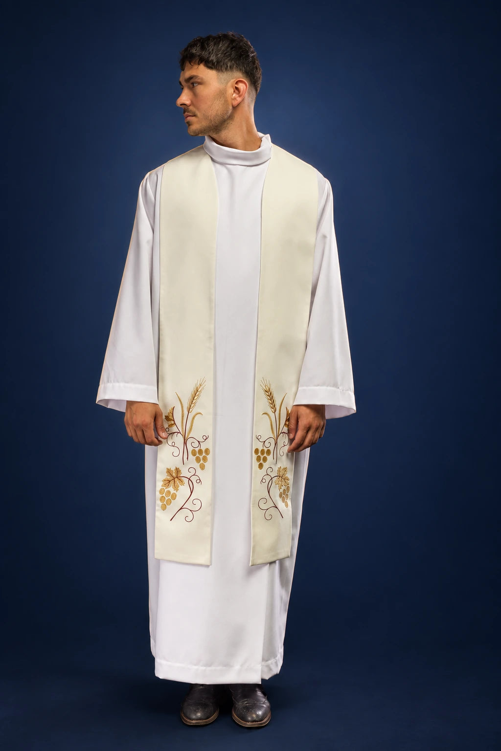 Front view of an ecru Catholic stole with embroidered grapes and wheat, worn over a white alb