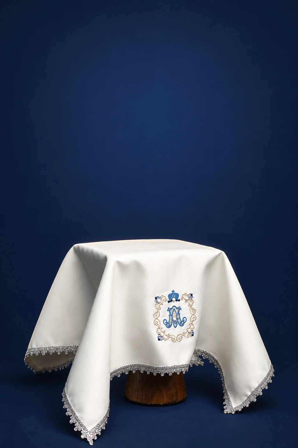 Front view of an ecru chalice veil with blue Marian embroidery and lace-trimmed edges
