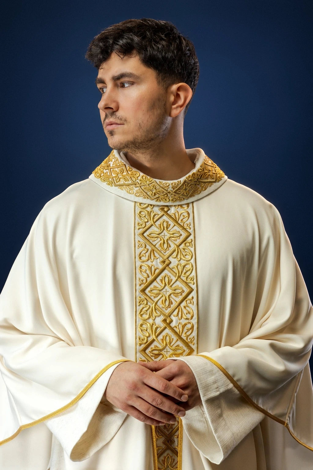 Front view of an ecru chasuble with gold floral embroidery and a vertical cross panel