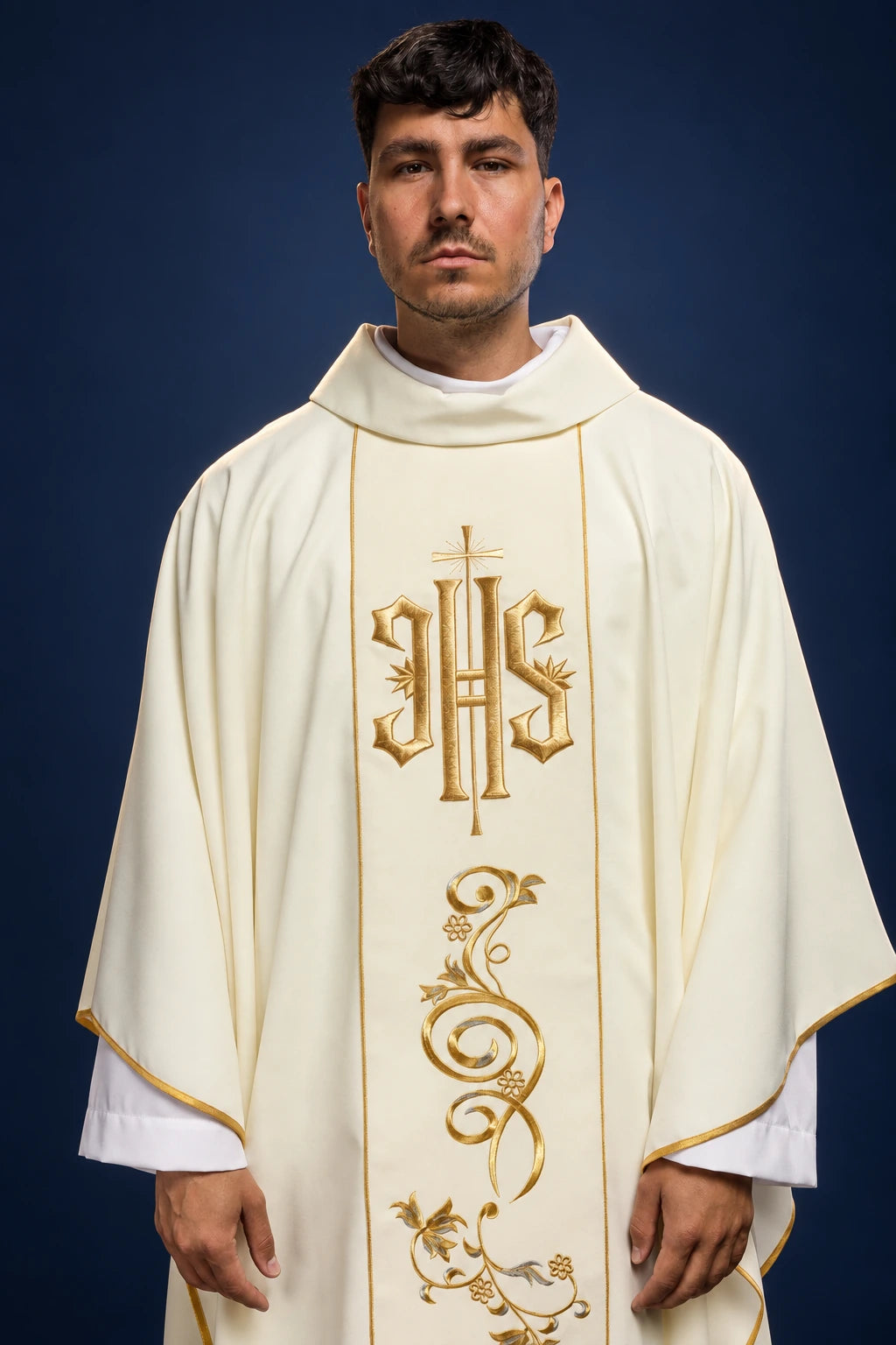 Front view of an ecru chasuble with gold IHS embroidery and vine scroll motif on the front panel