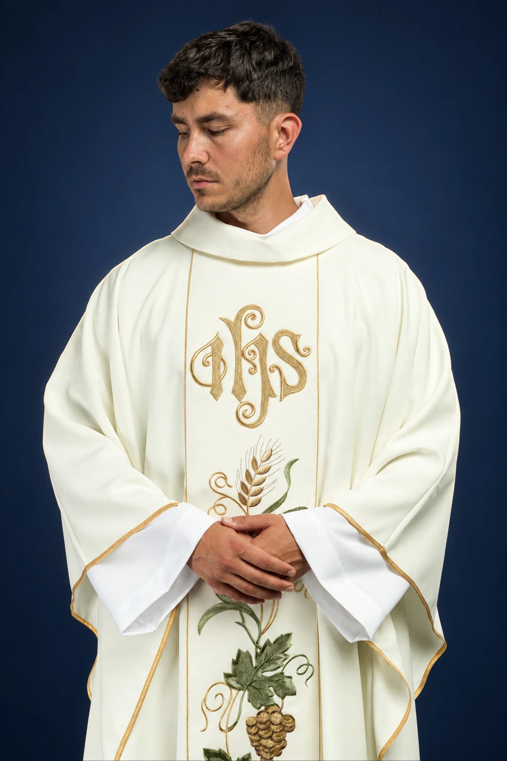 Front view of an ecru chasuble with gold IHS embroidery, wheat, and grape cluster motif