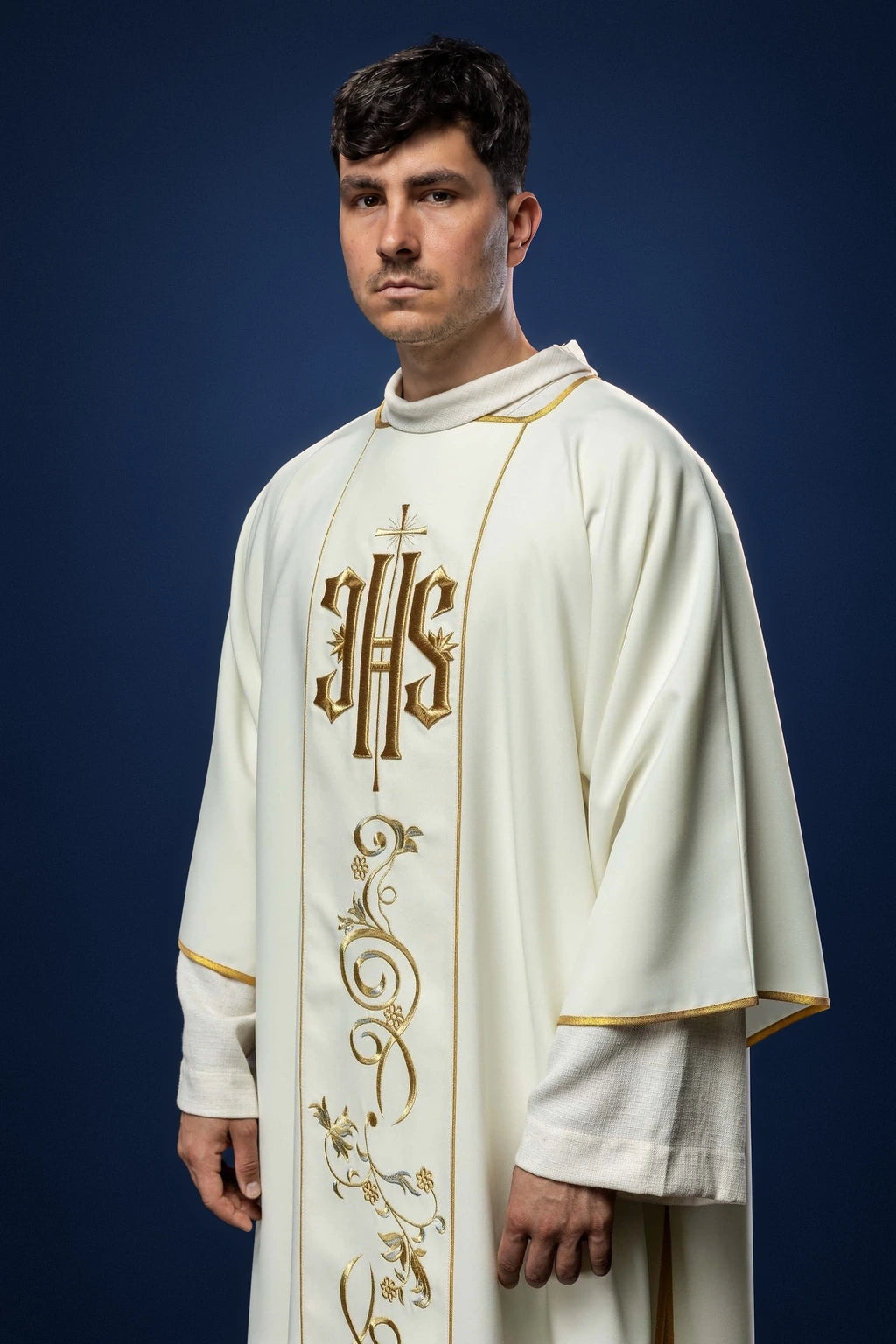 Front view of an ecru dalmatic with embroidered IHS orphrey and gold trim on the sleeves and front panel
