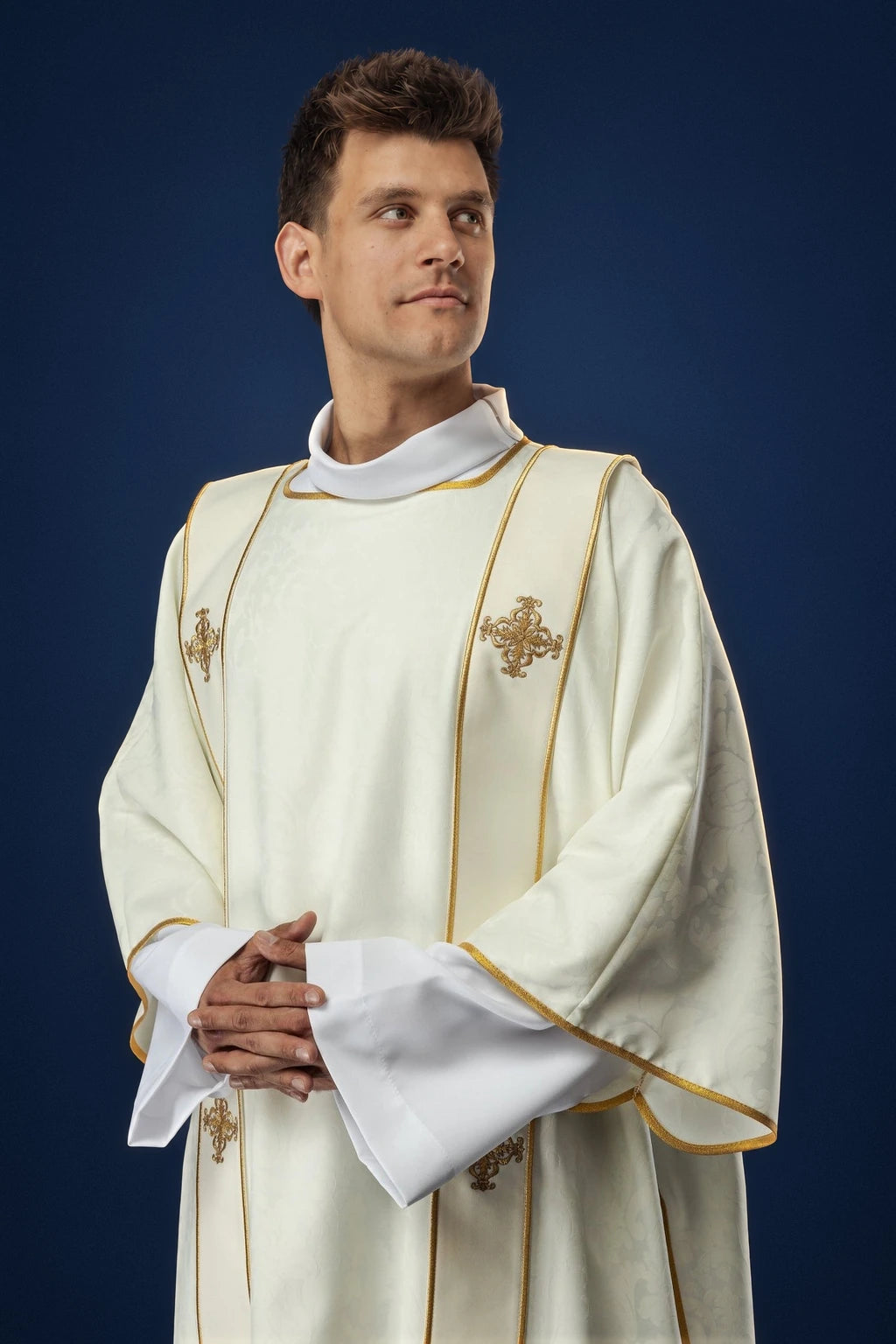 Front view of an ecru dalmatic with gold trim and embroidered crosses, worn over a white alb