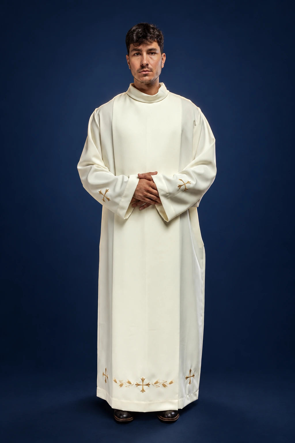Front view of an ecru priest alb with stand-up collar and gold cross embroidery along the hem and cuffs