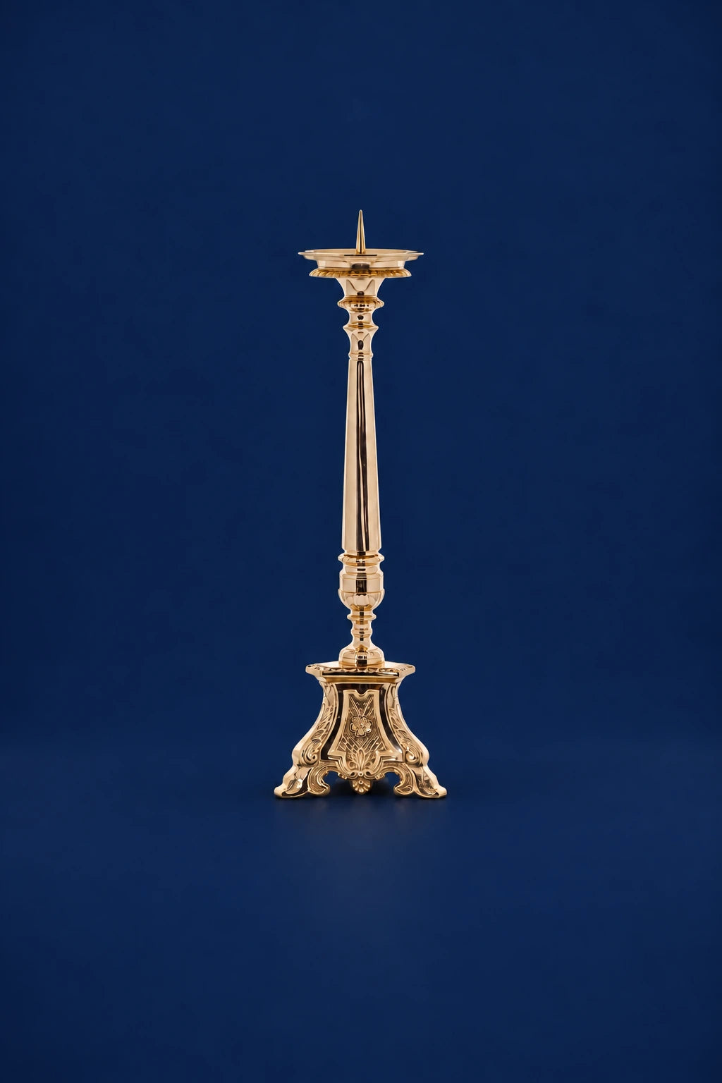 Front view of a gold-colored brass candlestick with ornate pedestal base and tall tapered stem