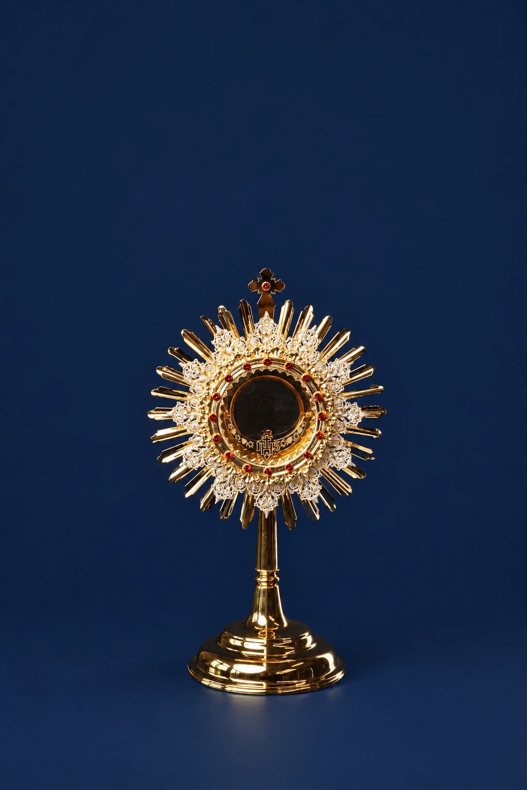 Front view of a gold-plated brass monstrance with a central ruby and radiating sunburst rays