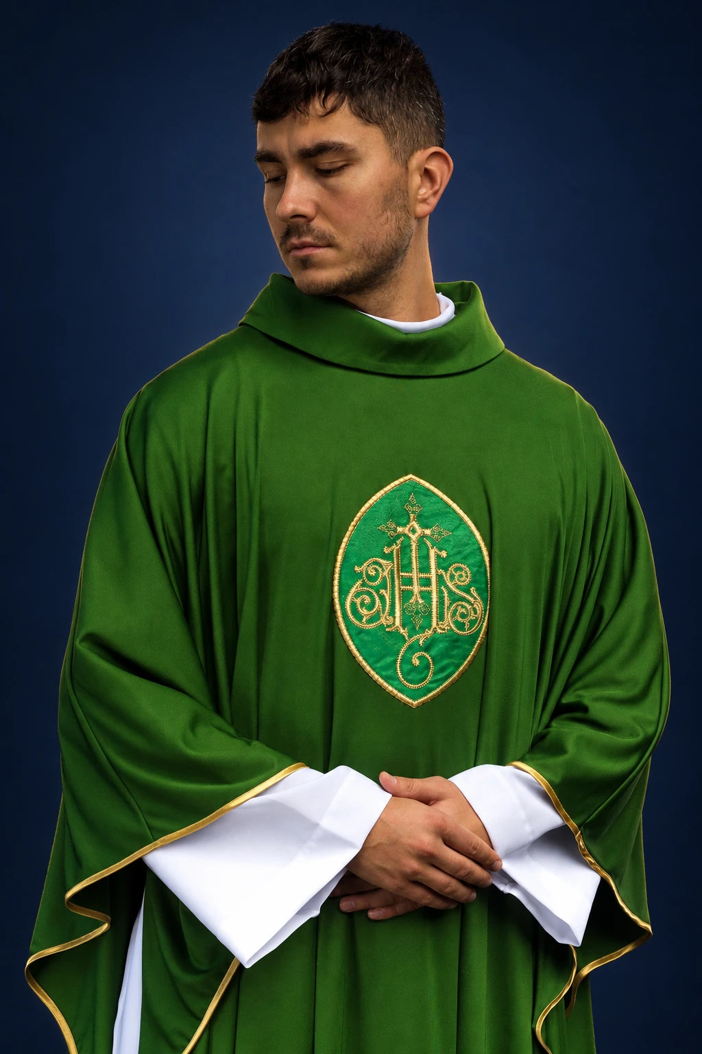 Front view of green chasuble with gold-edged embroidered monogram and white inner stole showing at the sleeves